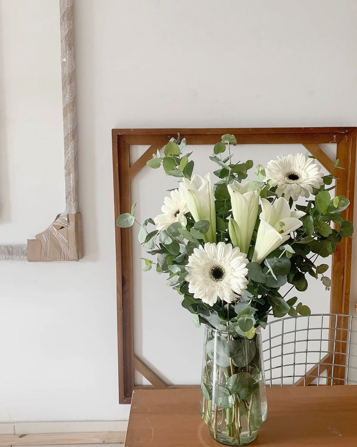 Arranjo de flores com folhagens e flores brancas.